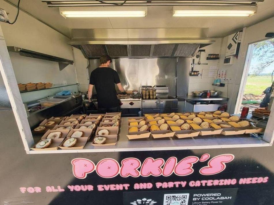 Inside the Porkie's servery — dozens of burgers boxed and lined up along the counter while the chef works the grill